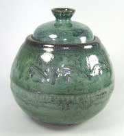 Glazed green pottery jar with a lid, featuring intricate texture and vibrant glossy finish, ideal for decorative purposes.