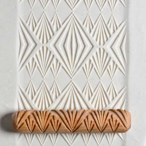 Textured white clay tile featuring geometric patterns, with a carved terracotta trim showcasing decorative ceramic techniques.