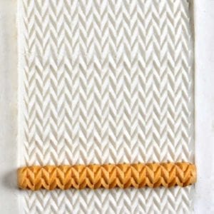 Textured white clay sheet showing a zigzag pattern, with a horizontal orange clay band at the bottom for decorative use.
