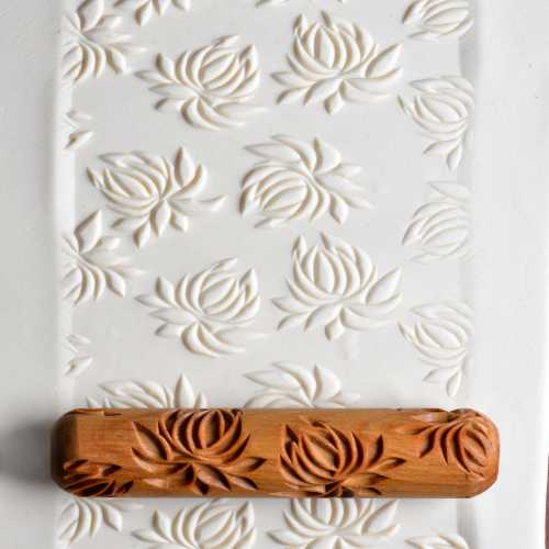 Embossed white clay with floral patterns, featuring a carved wooden texture roller from Georgies Ceramic & Clay Company.