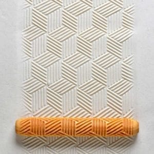 Textured clay surface featuring a geometric pattern, with a carved ceramic roller in orange at the bottom, used for decorating pottery.