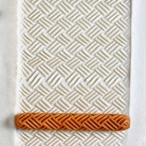 Textured white clay surface with an orange clay band, showcasing pattern techniques for pottery and ceramic decoration.