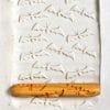 Textured white clay slab with intricate surface pattern and a wooden tool for marking or carving ceramic designs.