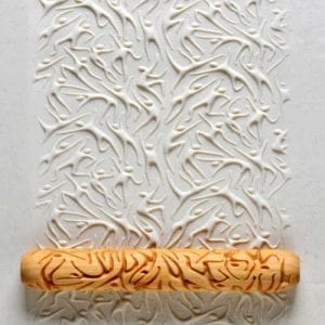 Decorative clay texture created with a patterned rolling pin, showcasing intricate designs on beige ceramic surface.