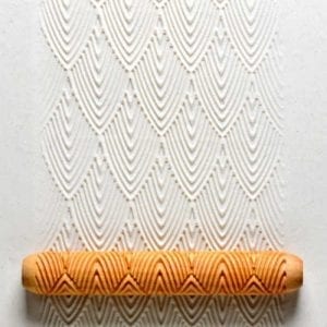 Textured ceramic surface with a rolling pin, showcasing a decorative wave pattern, ideal for pottery embellishment.