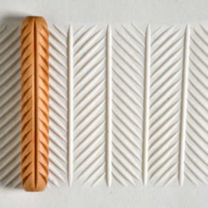 Ceramic texture roller pressed into clay, creating a herringbone pattern; tools for pottery decoration and surface design.