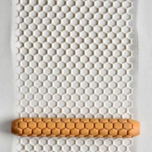 Textured white clay sheet with a hexagonal pattern being rolled with an orange clay stylus for ceramic decoration.