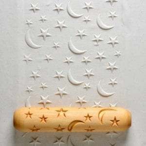 Textured clay surface showing clear imprints of stars and moons made with a wooden rolling pin designed for ceramics.