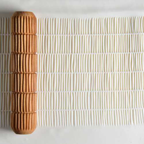 Textured clay surface with a ribbed wooden texture tool from Georgies, used for pottery and ceramic decoration.