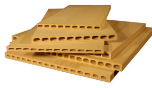 Stacked yellow humidification Masonite boards with hole patterns, used in ceramic studios for clay drying and work surface durability.