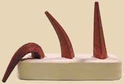 Ceramic sculpture featuring three elongated, textured cone shapes on a smooth clay base, showcasing fired terracotta glaze.
