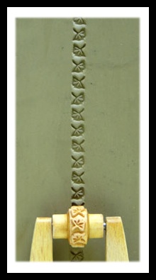 Impression of leaf pattern on a slab of green clay using a pottery roller tool, showcasing ceramic decorating techniques.