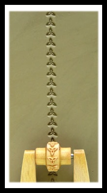 Clay sheet with an embossed pattern created by a ceramic texture roller, showcasing intricate designs on the surface.