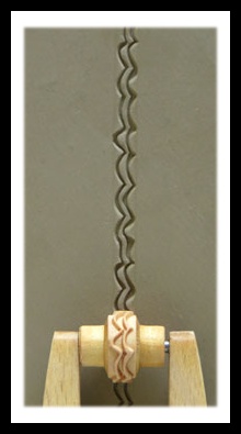 Ceramic texture roller creating a zigzag pattern on damp clay, showcasing a decorative technique for pottery.