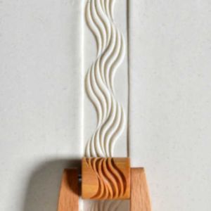 A textured clay slab with wavy patterns, supported by a wooden holder, showcasing ceramic design techniques.
