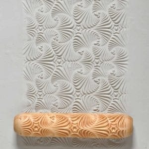 Decorative clay pattern created with a textured rolling pin, showcasing swirling designs pressed into white clay.