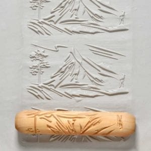A ceramic texture roller with a nature design presses into clay, leaving an intricate pattern for pottery decoration.