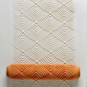 Textured clay surface with a wave pattern, showcasing a ceramic roller for imprinting designs on pottery.
