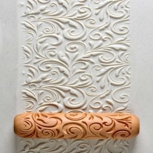 Decorative impression roller on clay creating an intricate swirl pattern, ideal for enhancing pottery and ceramic projects.