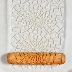 Textured clay slab with spiral pattern, rolled with a decorative wooden texture roller, showcasing ceramic surface design techniques.