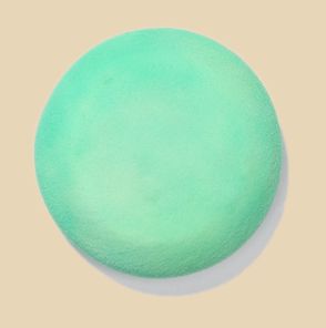 Green ceramic glaze sample on a round plate, showcasing a smooth, matte finish ideal for pottery decorating.