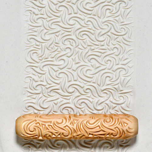 Textured clay surface with a decorative rolling pin, showcasing intricate swirl patterns for ceramic decoration.