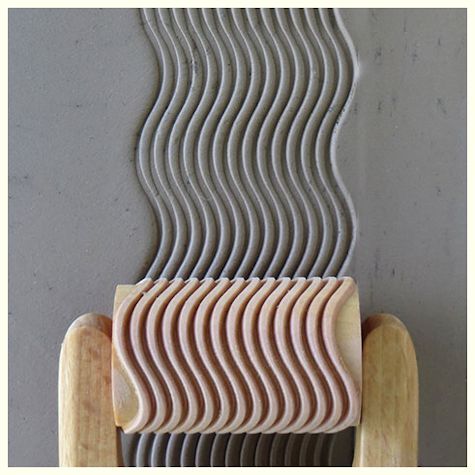 Textured gray clay rolled using a wave-patterned ceramic slab roller, showcasing a smooth, decorative finish.