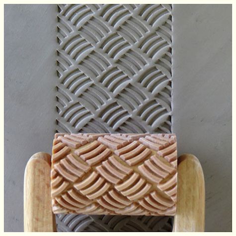 Ceramic texture roller imprinting a woven pattern on a slab of clay, showcasing tools for surface decoration in pottery.