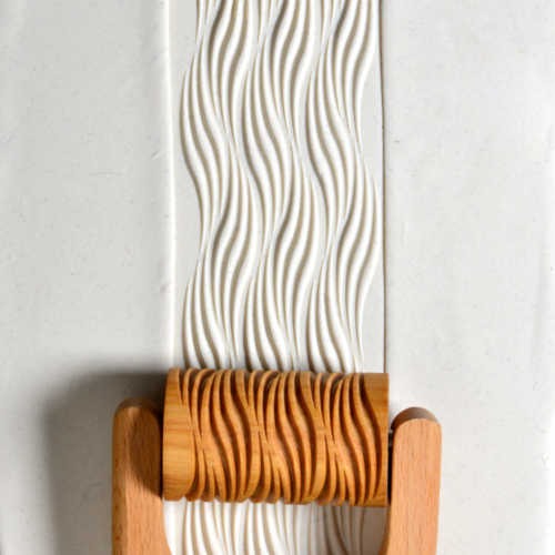 Textured white clay rolled with a wooden slab roller, featuring a wavy pattern, ideal for ceramic projects at Georgies.