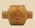 Carved clay roller with intricate face design, used for texture in pottery, ideal for surface decoration in ceramics.