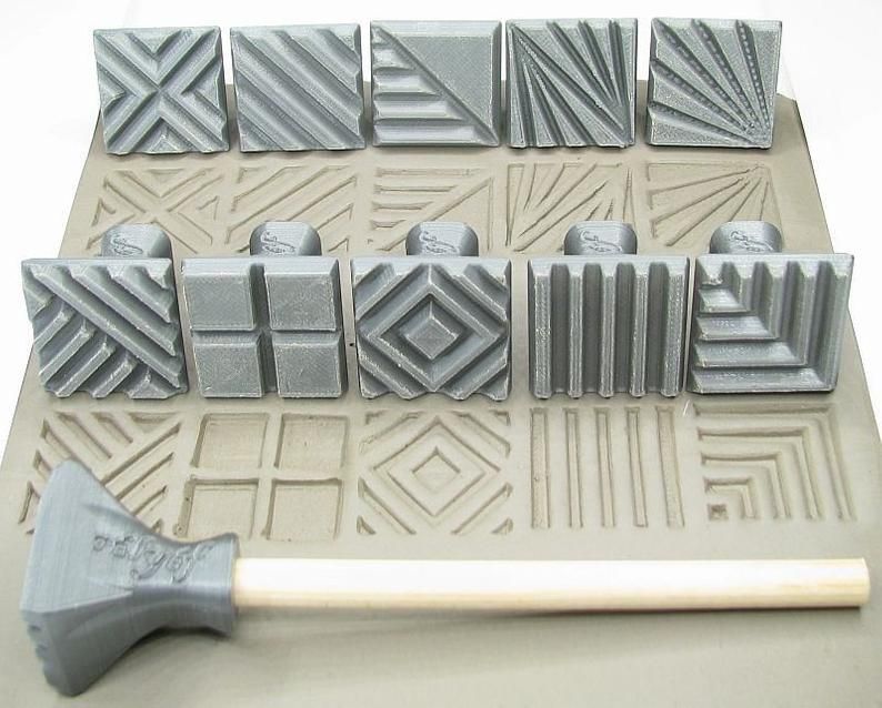 Various textured ceramic stamps on clay, with a wooden handle tool for imprinting designs; ideal for pottery decoration.