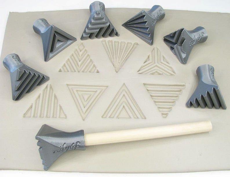 Set of ceramic texture tools on clay, featuring various triangle patterns and a wooden handle for ceramic decoration techniques.