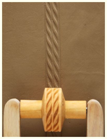 Ceramic clay with a textured design made using a wooden stamp tool, showcasing decorative detailing for pottery.