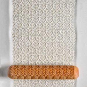 Textured clay slab with a leaf pattern, rolled with a paddle stamp tool, used for pottery decorating and design techniques.
