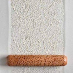 Textured clay slab with leaf patterns rolled out using a wooden clay roller, ideal for ceramic decorating at Georgies.