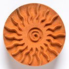 Terracotta clay disc with a sun motif, featuring raised rays and a spiral center, suitable for pottery decoration or casting.
