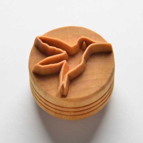 A round terracotta ceramic stamp featuring a detailed hummingbird design, ideal for decorating pottery and clay projects.