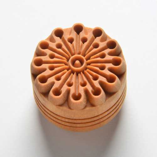 Ceramic texture stamp featuring a floral design, ideal for decorating clay and pottery, made from durable orange material.