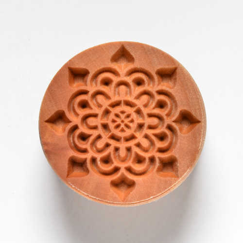 Terracotta clay stamp featuring an intricate floral design, ideal for decorating pottery or ceramics.