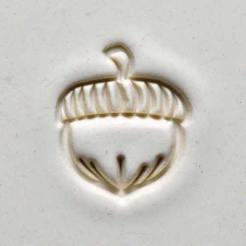 Detailed imprint of an acorn design on a slab of fine white clay, ideal for ceramic projects and decorative pottery.