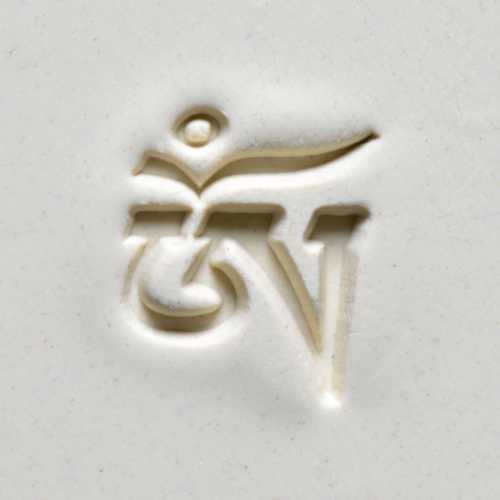Close-up of an intricately carved clay tile featuring a stylized symbol, showcasing texture for ceramic decoration.