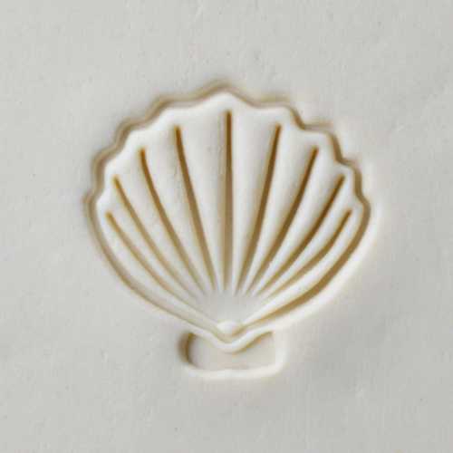 A detailed impression of a shell design in soft clay, ideal for ceramic decoration or relief sculpture work.