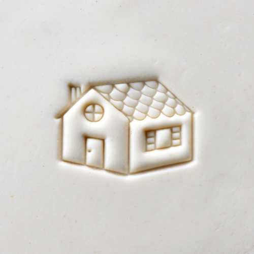 Embossed house design on white clay, showcasing ceramic texture ideal for decorating pottery.