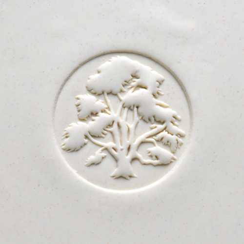 Relief design of a tree emblem on a white ceramic surface, showcasing texture and craftsmanship in pottery.