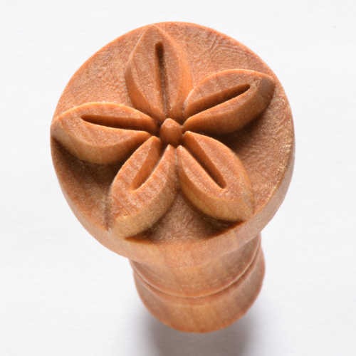 Carved wooden ceramic stamp with a flower design, used for decorating pottery and clay projects.