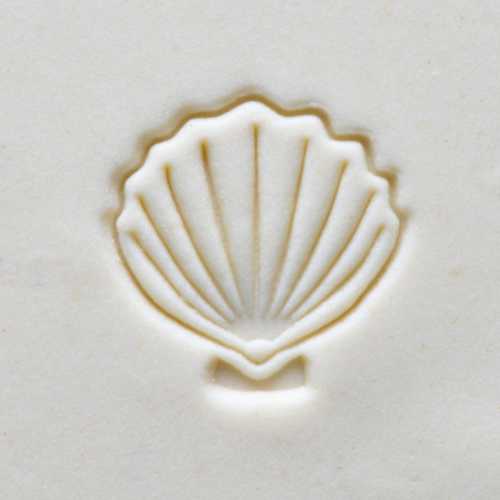 Impression of a scallop shell on creamy clay, showcasing texture for decorative ceramic projects or sculpting.