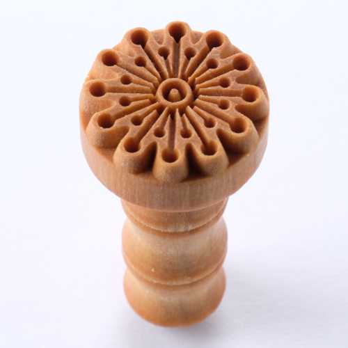 Ceramic texture stamp with intricate floral pattern, used for decorating pottery and sculpting clay. Ideal for texturing.