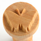 Detail of a wooden stamp featuring a butterfly design, used for decorating pottery and clay projects at Georgies Ceramic & Clay Company.