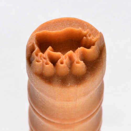 Close-up of a clay texture stamp used for ceramics, featuring a detailed design for decorating pottery surfaces.