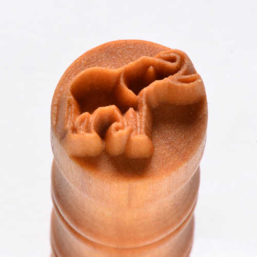 A close-up of a ceramic stamp featuring a camel design, ideal for decorating pottery or clay projects.
